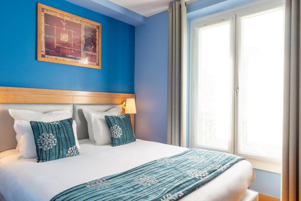 a bedroom with blue walls and a bed with pillows at Grand Hotel Dore in Paris