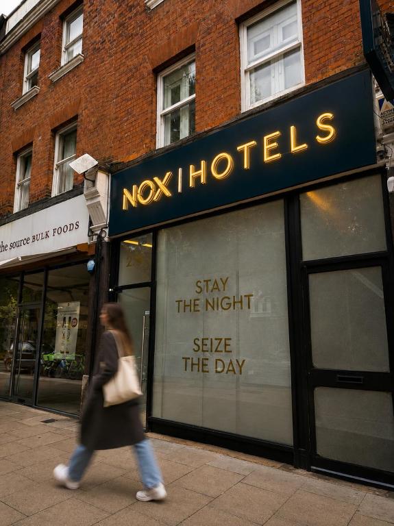 a woman walking in front of a ny nightclubessions window at NOX West Hampstead in London