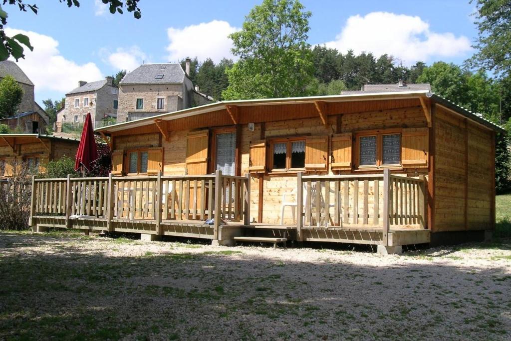 a wooden house with a porch and a fence at Camping de Saint Just - Onlycamp in Arcomie