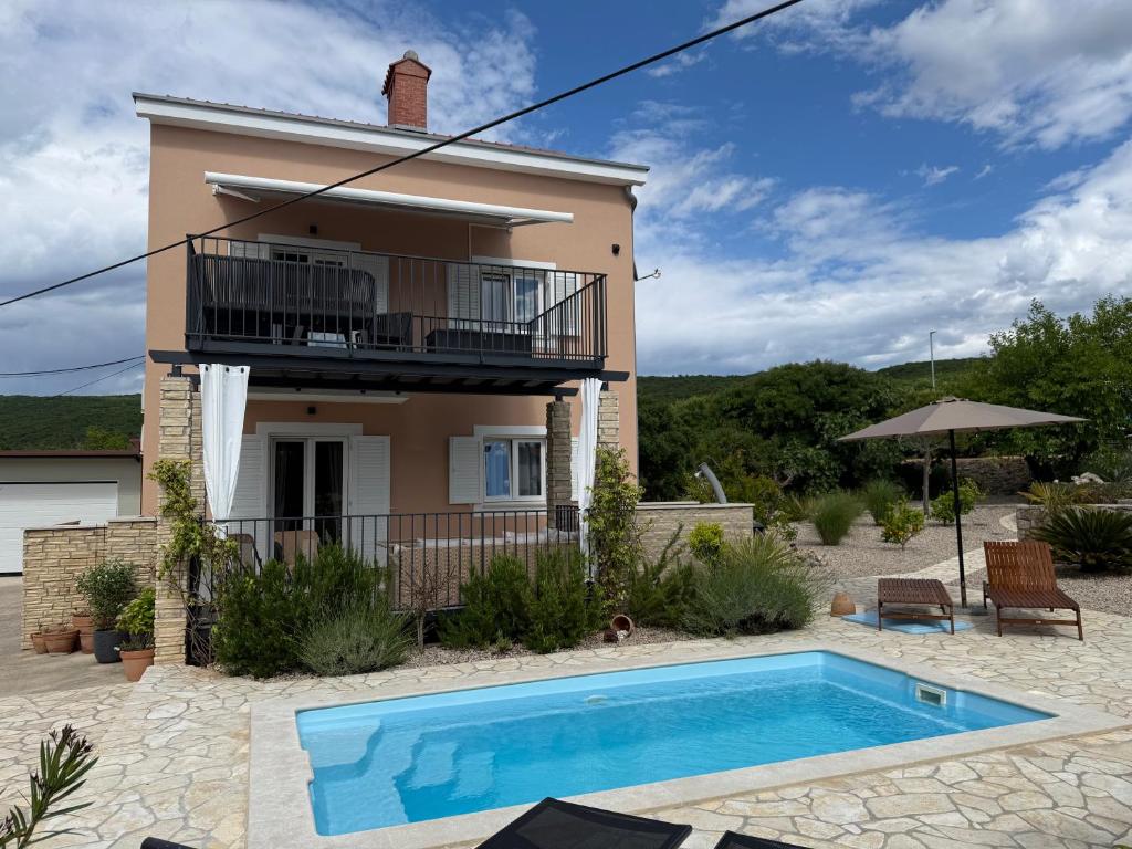 a villa with a swimming pool in front of a house at Kuća Koza-Apartment Marijana in Punat