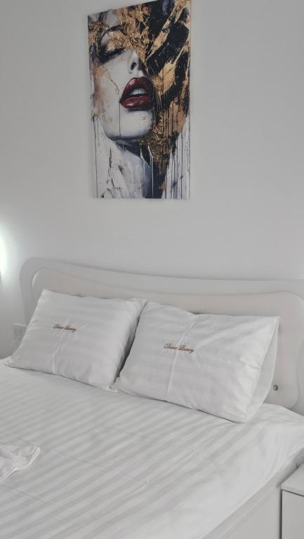 a bed with white sheets and a painting on the wall at Divine Luxury Rasnov in Râşnov