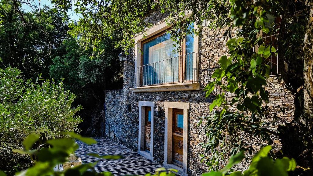 a stone house with a balcony on the side of it at Aguilhões River House in Pedorido