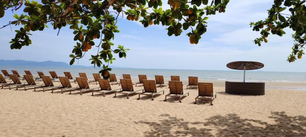 a row of chairs and an umbrella on the beach at Pattaya Private Beach - Grand Florida Beachfront Condo Resort in Na Jomtien