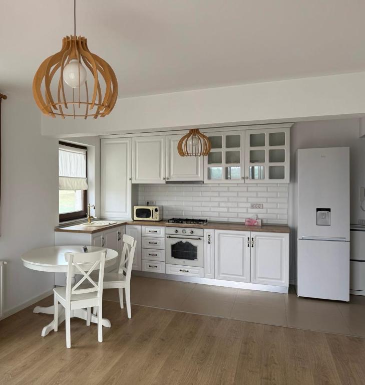 a white kitchen with a table and a white refrigerator at Magnolia Residence Premium in Găgeni