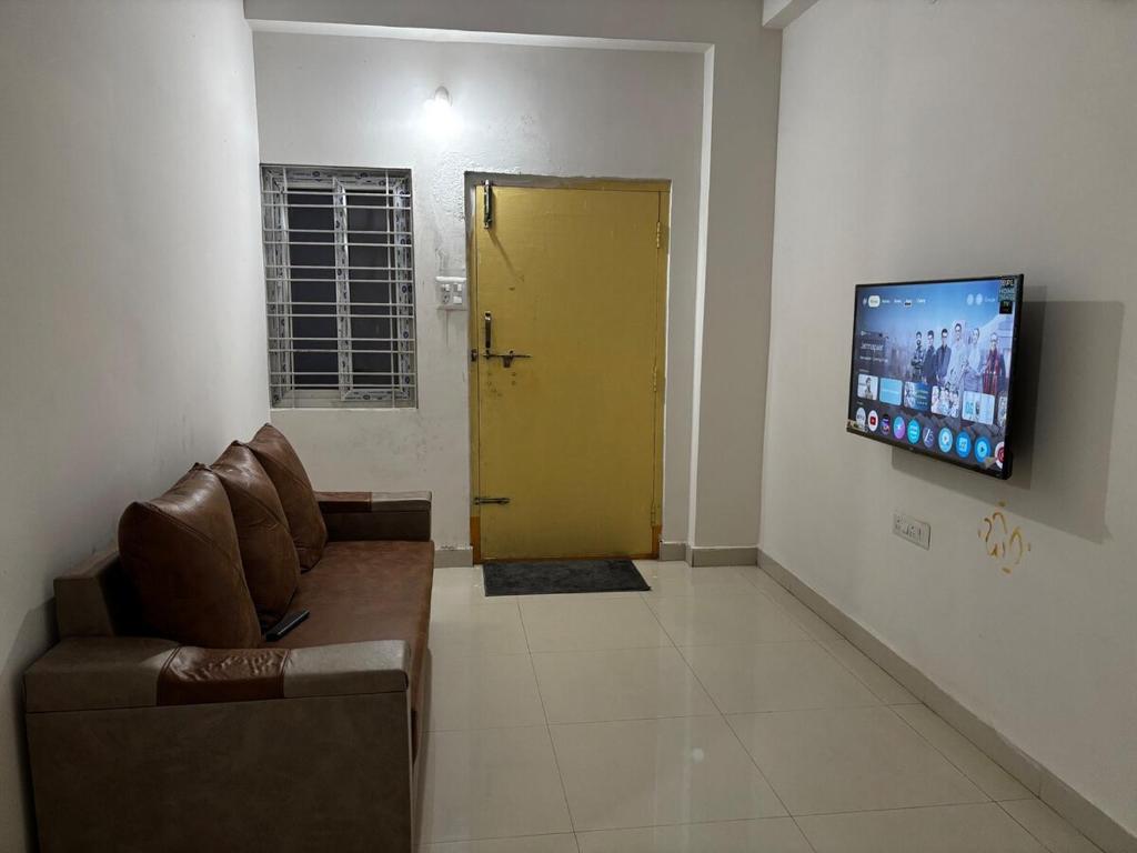 a living room with a couch and a yellow door at Odranest Serviced Apartment in Secunderabad