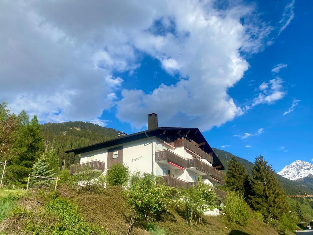 a house on a hill with mountains in the background at Haus Anemona in Savognin