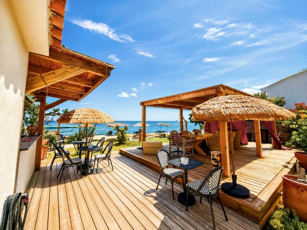 a wooden deck with chairs and tables and umbrellas at Maison "LA ROSALINDA-2B" Ghisonaccia in Ghisonaccia