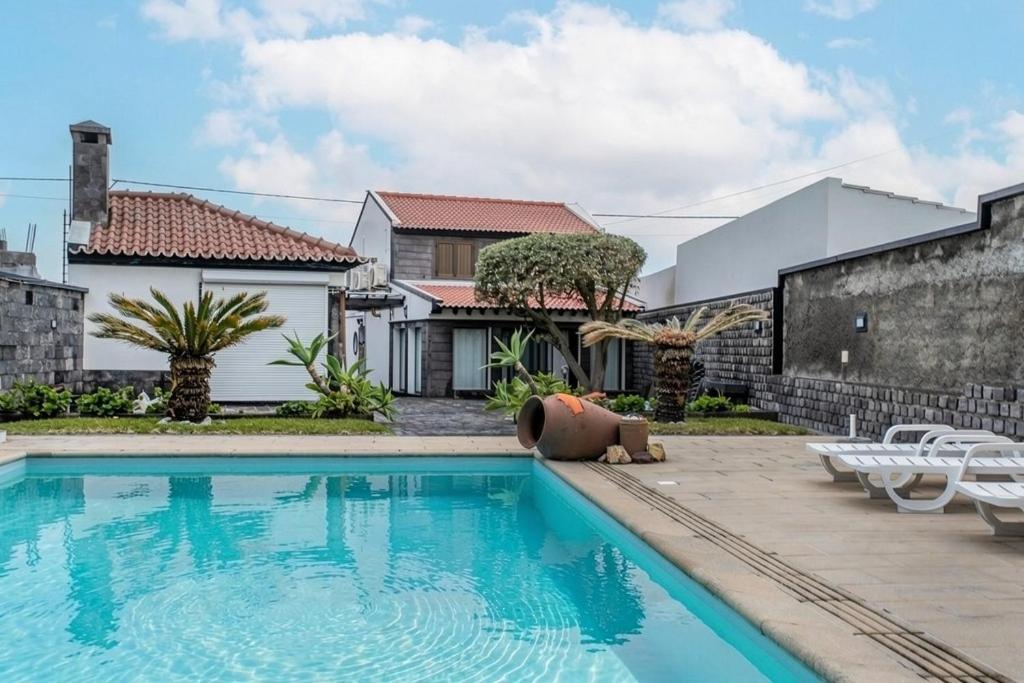 a swimming pool in front of a house at Heated Saltwater Pool-Private Beachside Oasis in Mosteiros