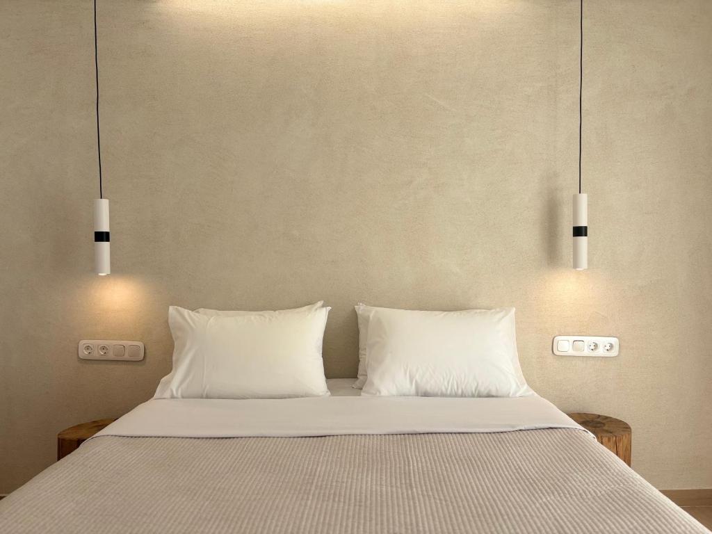 a bed with two pillows and two lights above it at Hotel Faros in Ios Chora