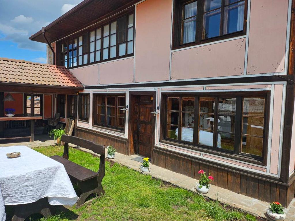 a house with a table and a bench in the yard at Карагьозовата Къща - цяла къща - 6 големи спални, 6 бани и отделна механа in Koprivshtitsa
