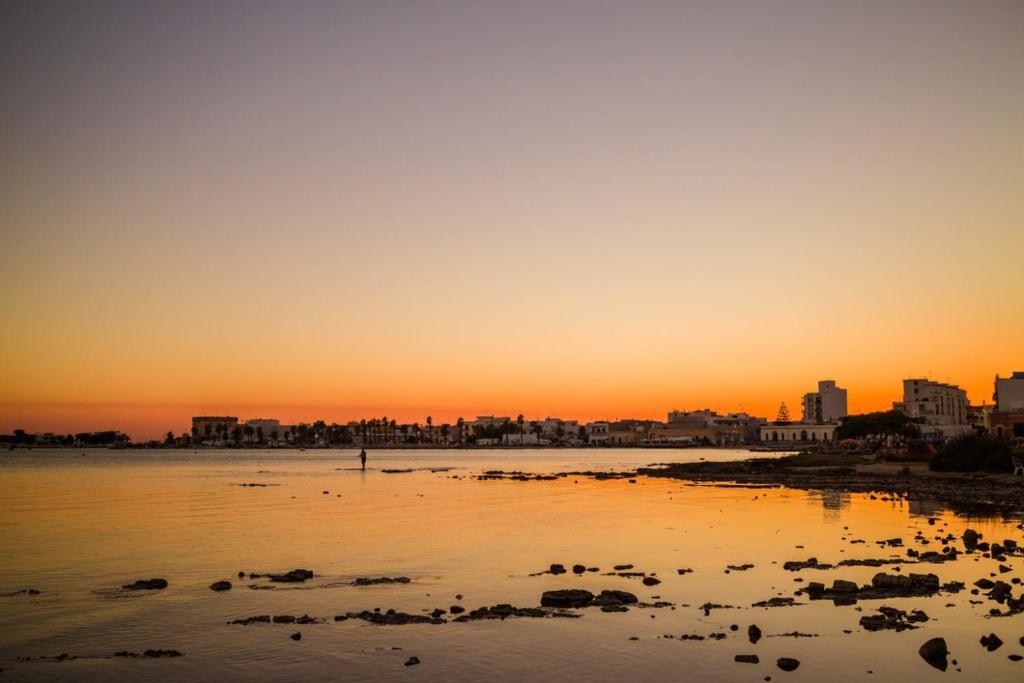 a sunset over a body of water with a city at Hotiday Porto Cesareo in Porto Cesareo