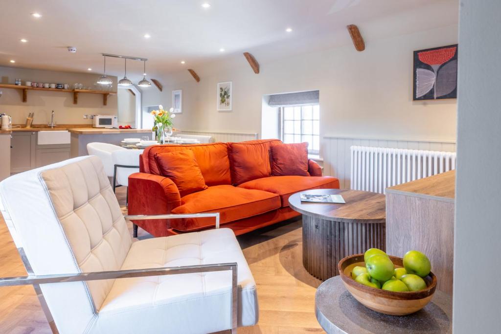 a living room with an orange couch and a kitchen at 16 Ulph Place in Burnham Market