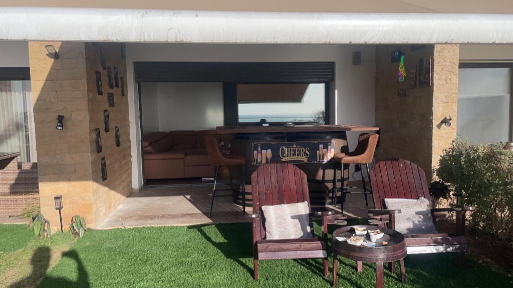 a house with two chairs and a table in a yard at OCEAN VIEW, Prestigia Plage des Nations in Sidi Bouqnadel