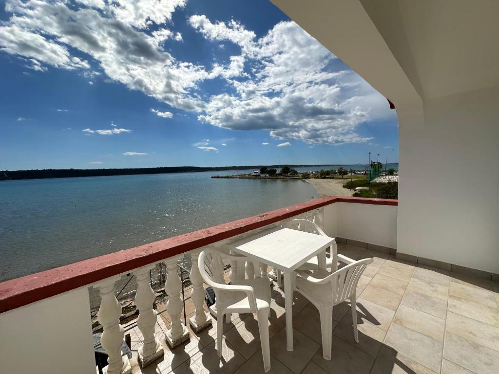 a balcony with a table and chairs overlooking the water at Apartment 2 (+1) in Ljubač