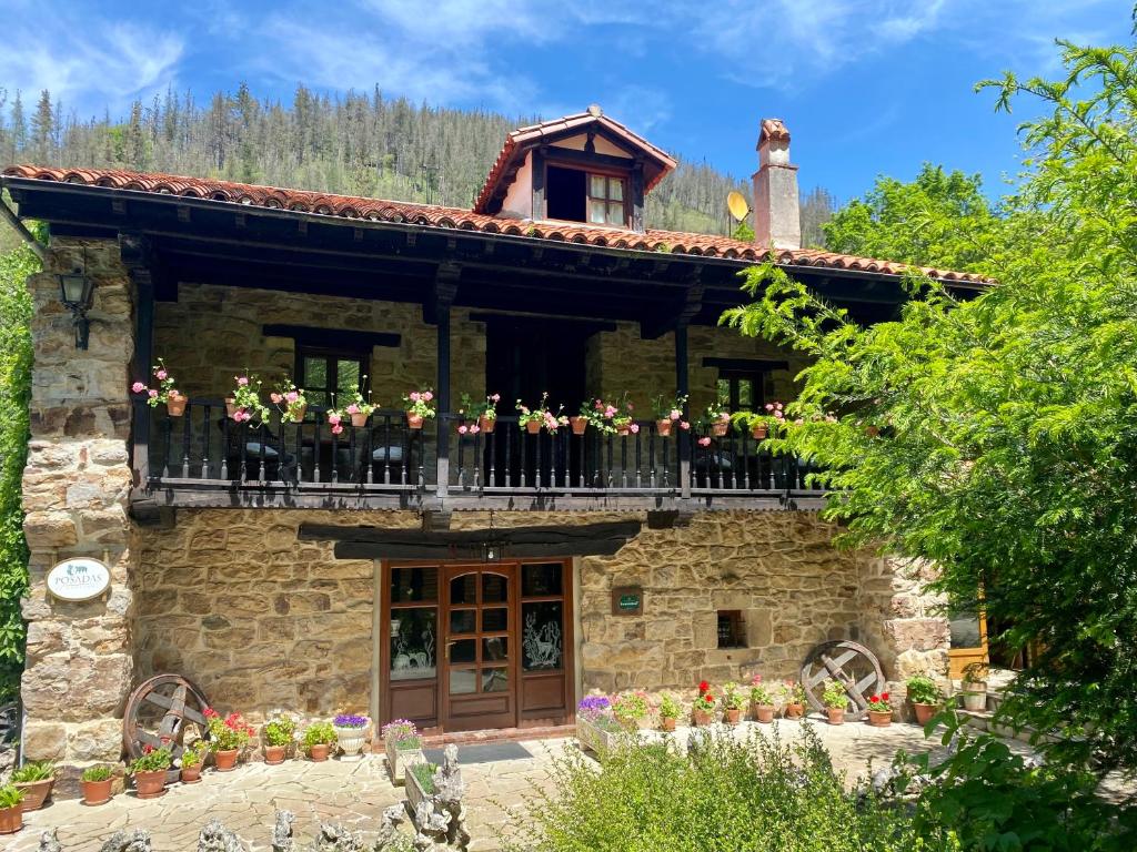 a building with a balcony with flowers on it at Posada la Punvieja in Los Tojos