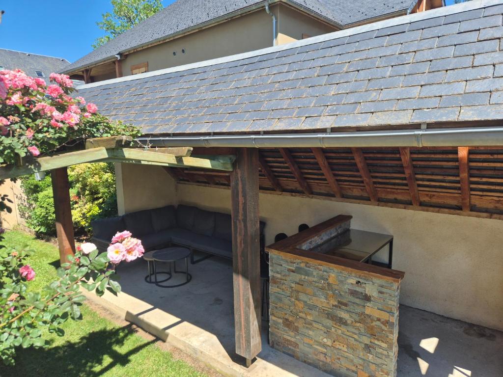 a patio under a roof with a bench and a table at Le nid des Pyrénées in Vielle-Aure