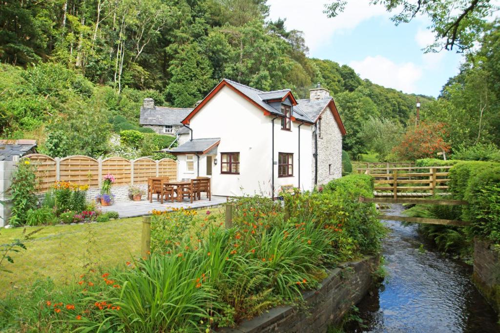 a cottage next to a river with a bridge at Hen Gapel in Aberhosan