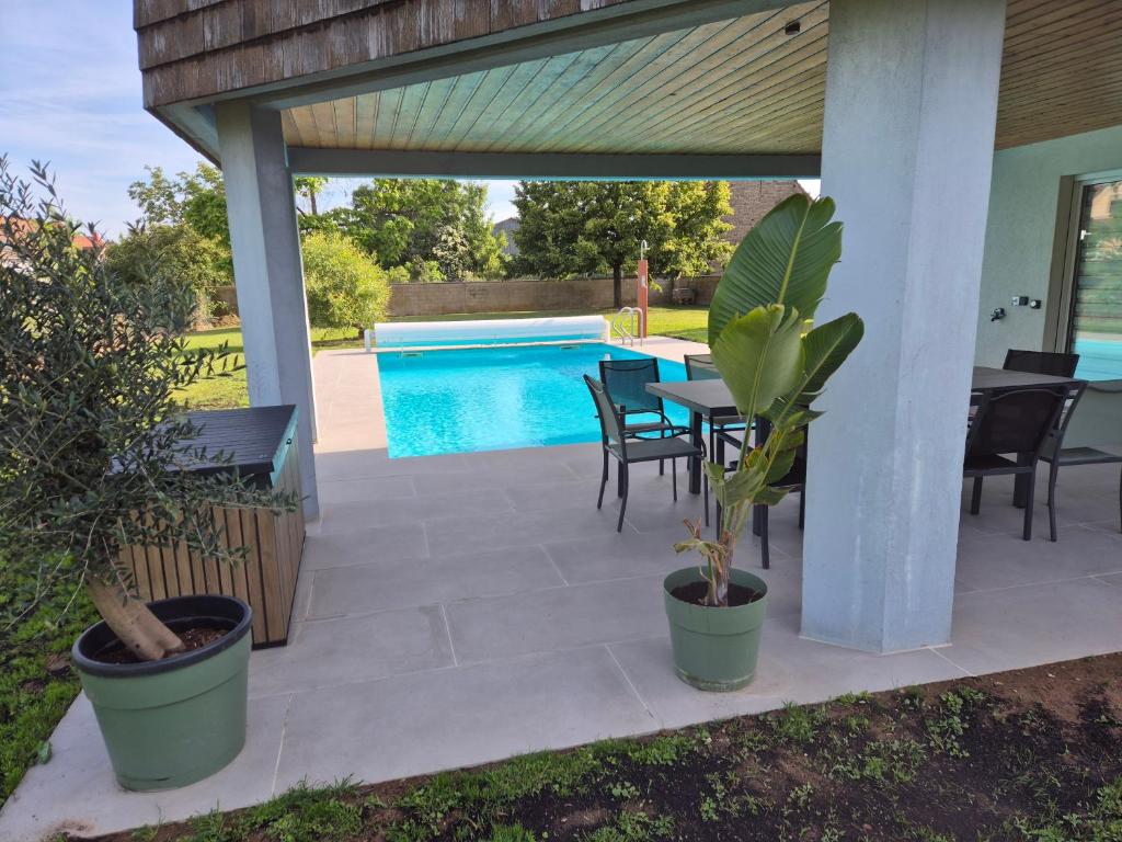 a patio with a table and chairs and a pool at Villa La Digue in Plobsheim