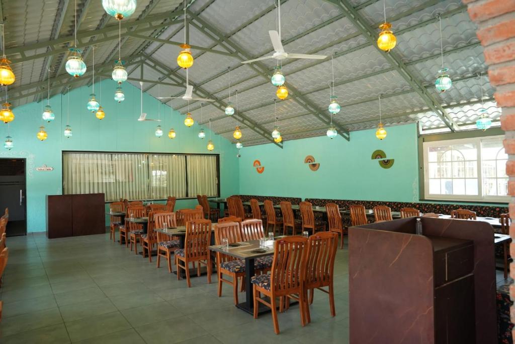 a dining room with tables and chairs and lights at Amorae Resort in Loni Khurd