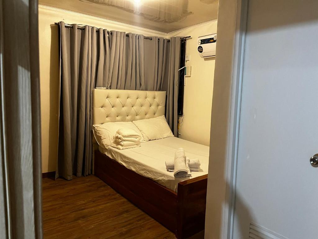 a small bed in a small room with a window at Travellers Staycation in San Jose del Monte