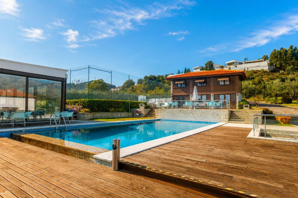 a house with a swimming pool and a wooden deck at Quinta da Eira do Sol in Guimarães