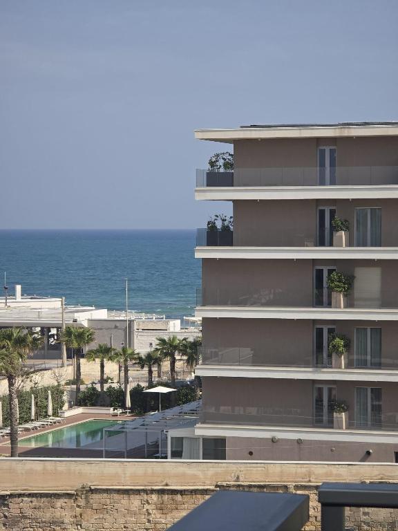 a building with a swimming pool next to the ocean at Levante Land & Sea in Bari