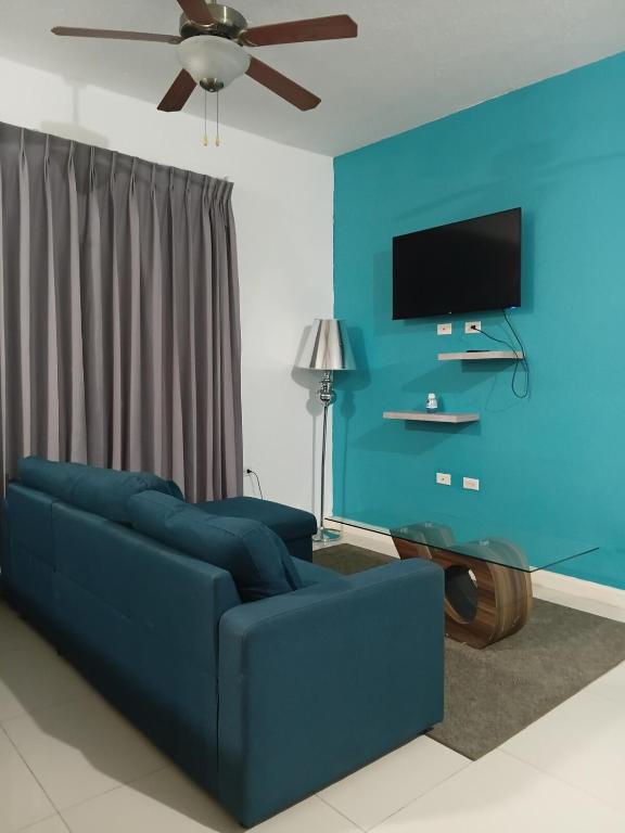 a living room with a blue couch and a flat screen tv at Kingston Condo with Rooftop Pool & Gazebo in Kingston