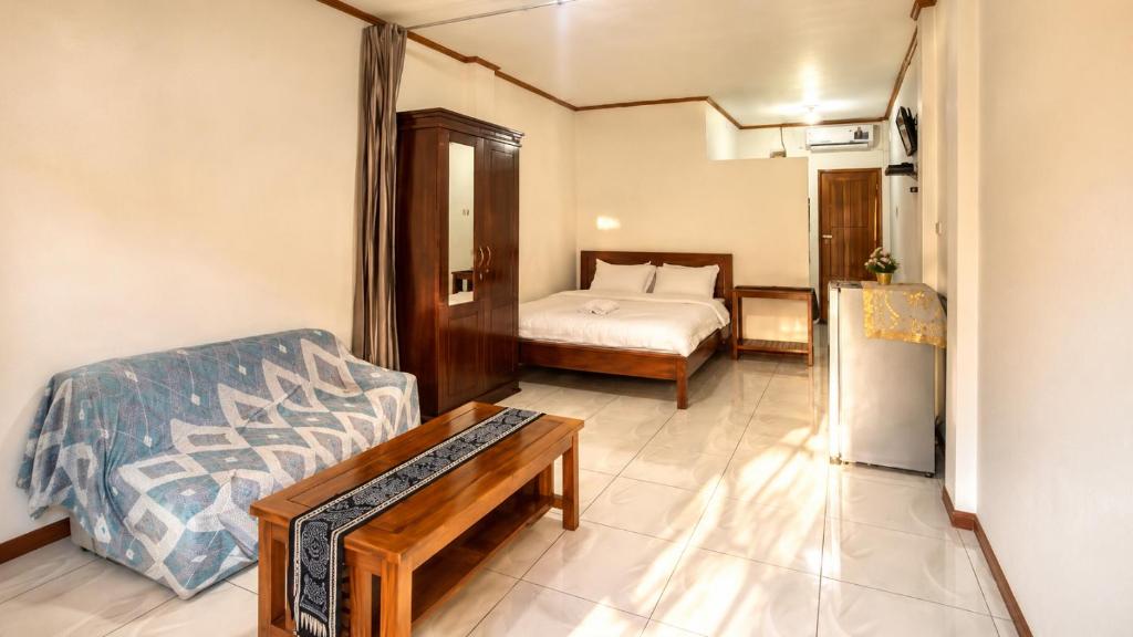 a room with a bed and a couch and a refrigerator at Ocha Bajo Homestay in Komodo Labuan Bajo Airport