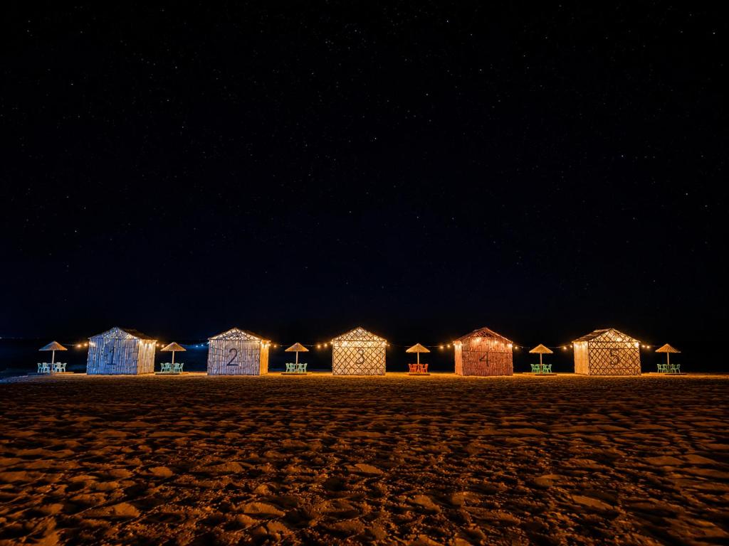 a row of beach huts lit up at night at Espace Azaimi in Tarîfa