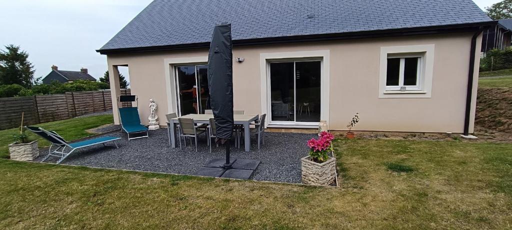 a patio with a table and chairs in front of a house at Le Mimosa in Cricquebœuf