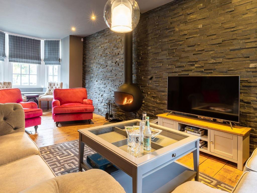 a living room with a tv and a brick wall at Prospect House in Windermere