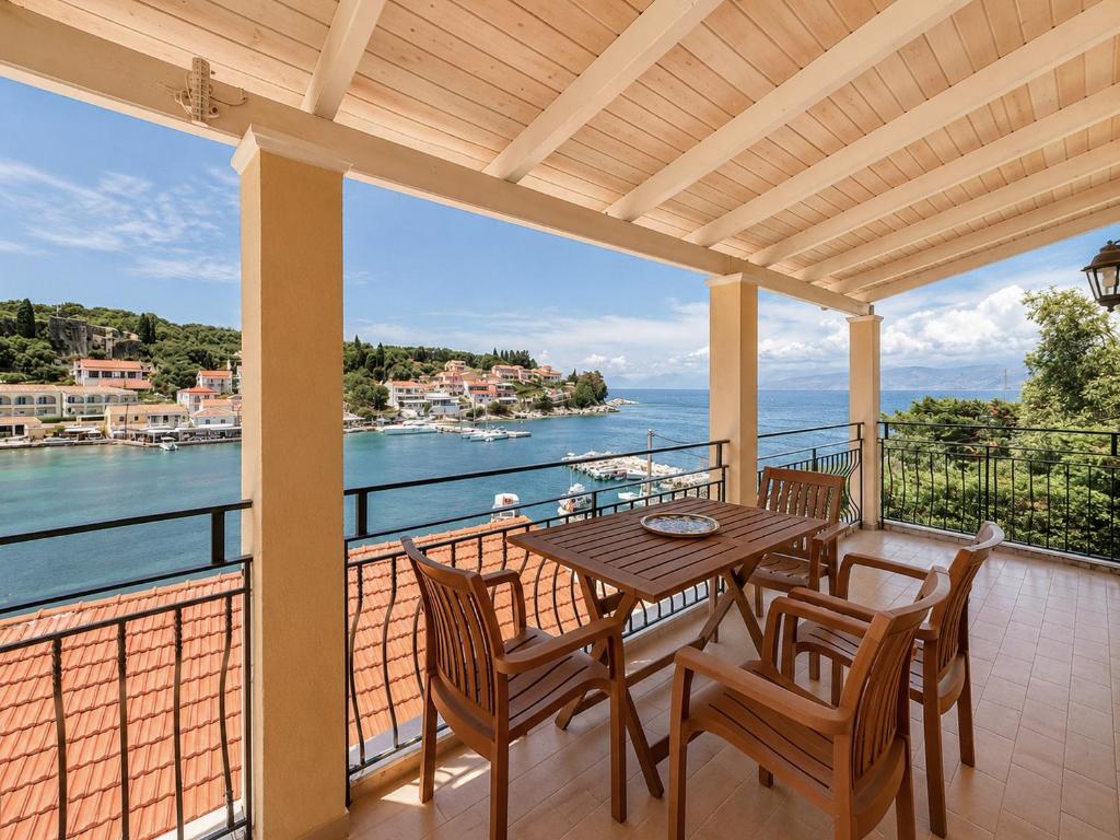 a balcony with a table and chairs and a view of the water at Virginia's Penthouse in Kassiopi