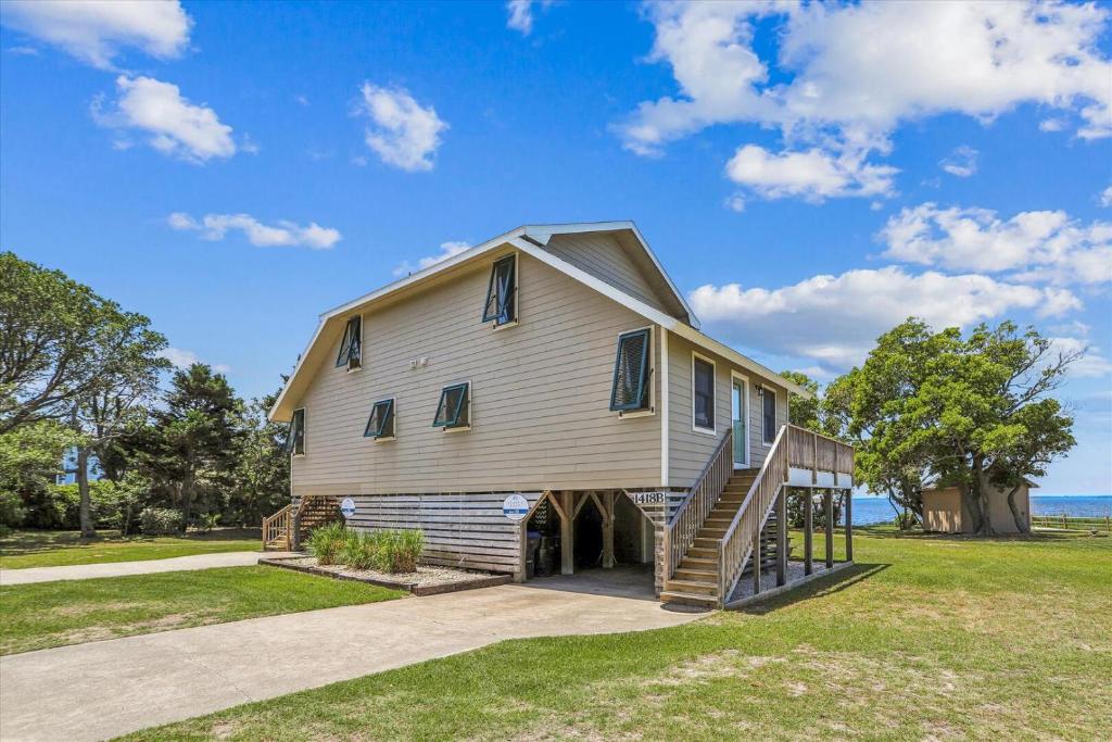 a large white house with a porch and stairs at Emerald Duck in Duck