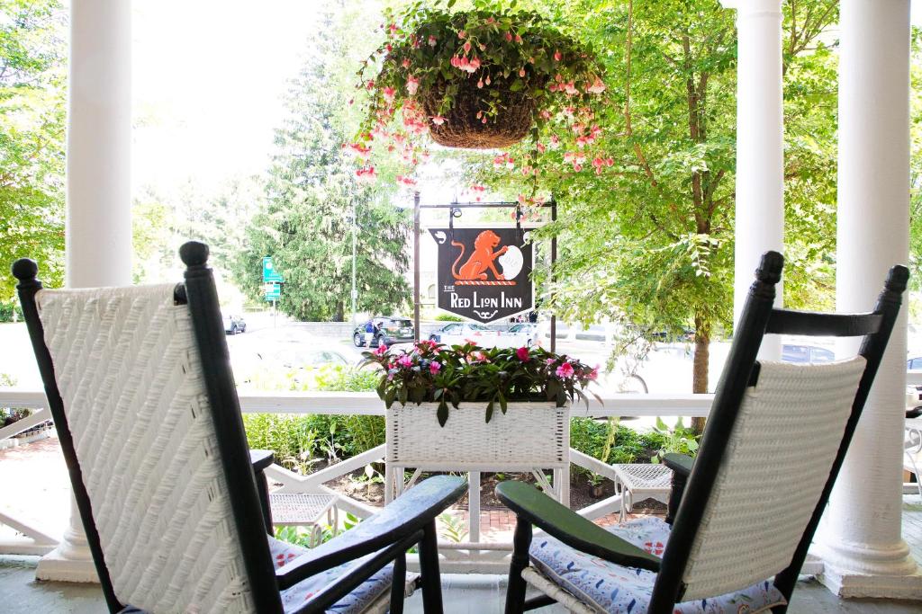 a porch with two chairs and a table with flowers at The Red Lion Inn in Stockbridge