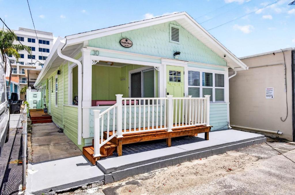 a green and white house with a porch at Island Vibes House in Clearwater Beach