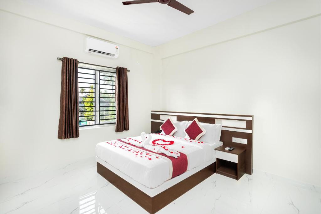 a white bedroom with a large bed with red pillows at Hotel Livora in Alwaye