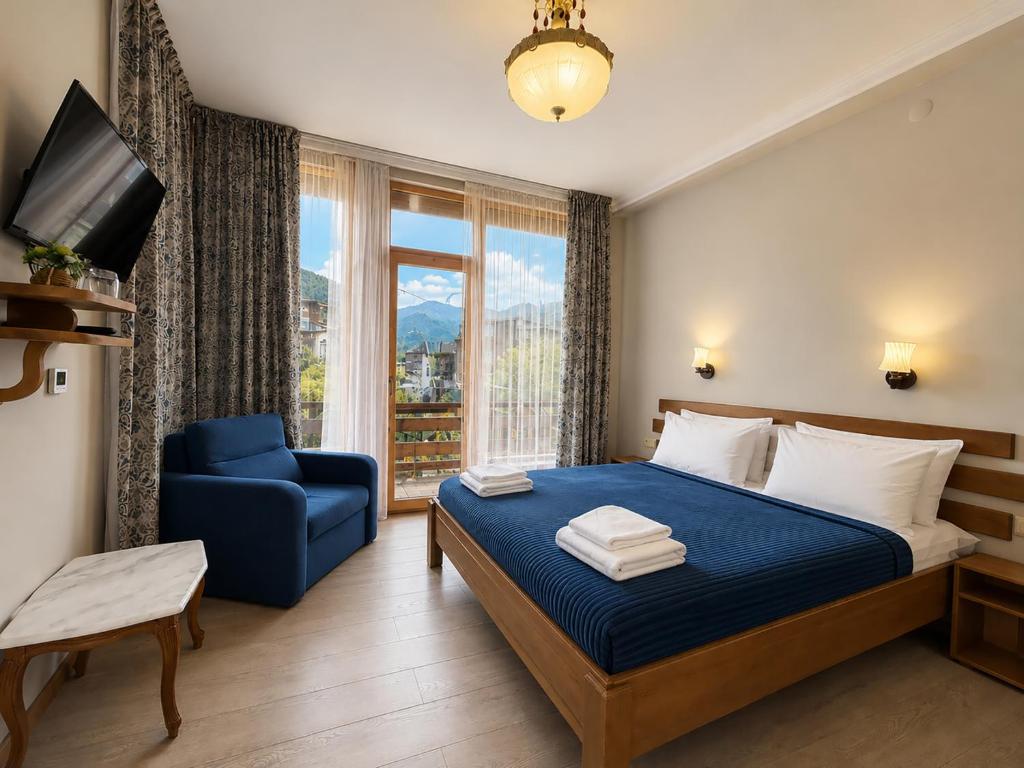 a bedroom with a blue bed and a chair and a window at Hotel Old Seti in Mestia