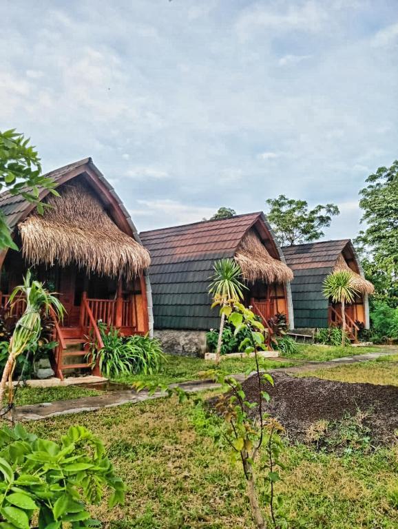 two houses with thatched roofs in a field at Bilva Garden Penida in Polilit