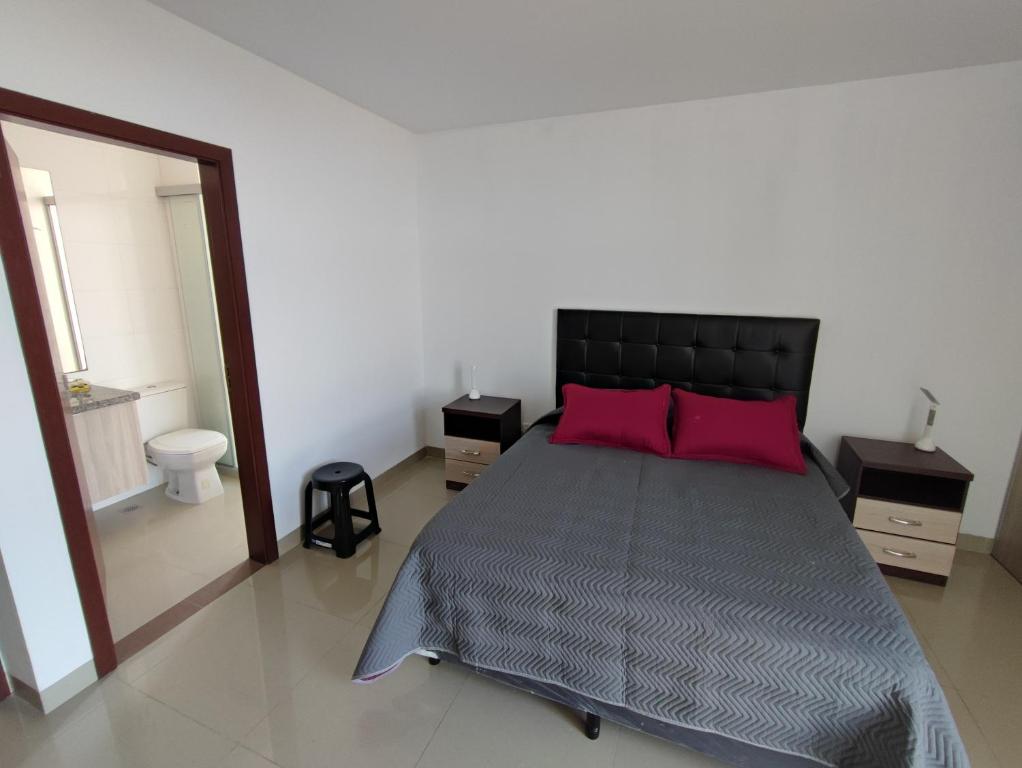 a bedroom with a bed with two red pillows at Vista Urbana Atlantis in Santa Cruz de la Sierra