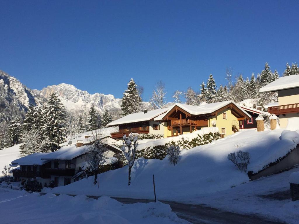 una casa cubierta de nieve junto a una montaña en Landhaus Constantin Luxus-Appartments en Berchtesgaden