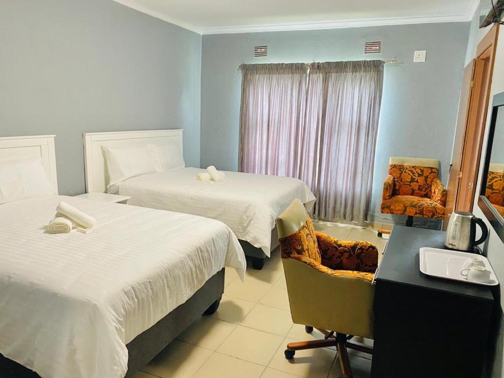 a hotel room with two beds and a chair at Mabutane Villas in Badplaas