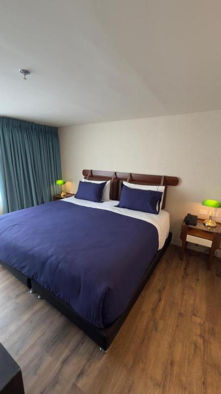 a bedroom with a large bed with blue sheets at Hotel Oliver in Bogotá