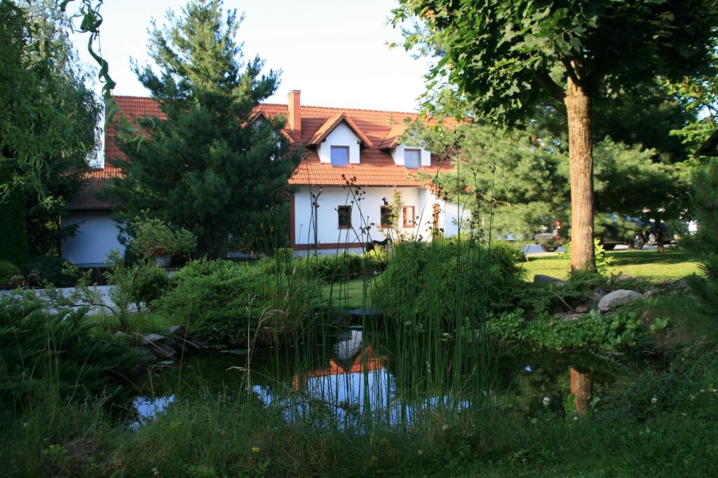une maison avec un étang en face de celle-ci dans l'établissement Słoneczne Siedlisko, à Wąglikowice