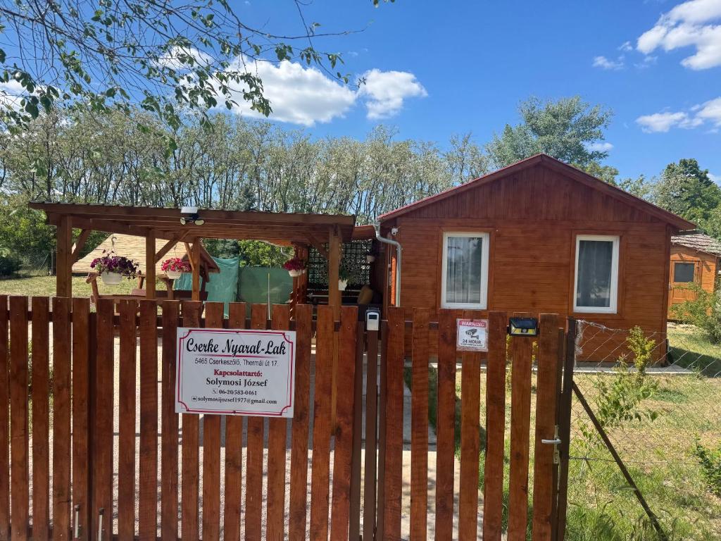 a log cabin behind a fence with a sign at Cserke Nyaral-Lak in Cserkeszőlő