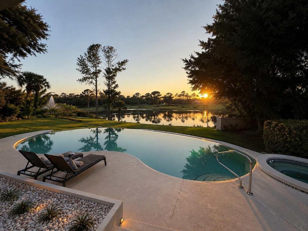 a swimming pool with two lounge chairs and a sunset at SWISS 28 - Lake Stephanie in Clermont