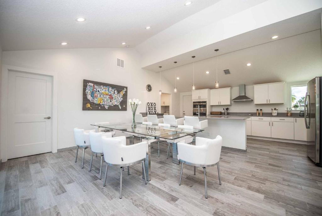a kitchen and dining room with a table and white chairs at SWISS 14 - Lake Stephanie in Clermont