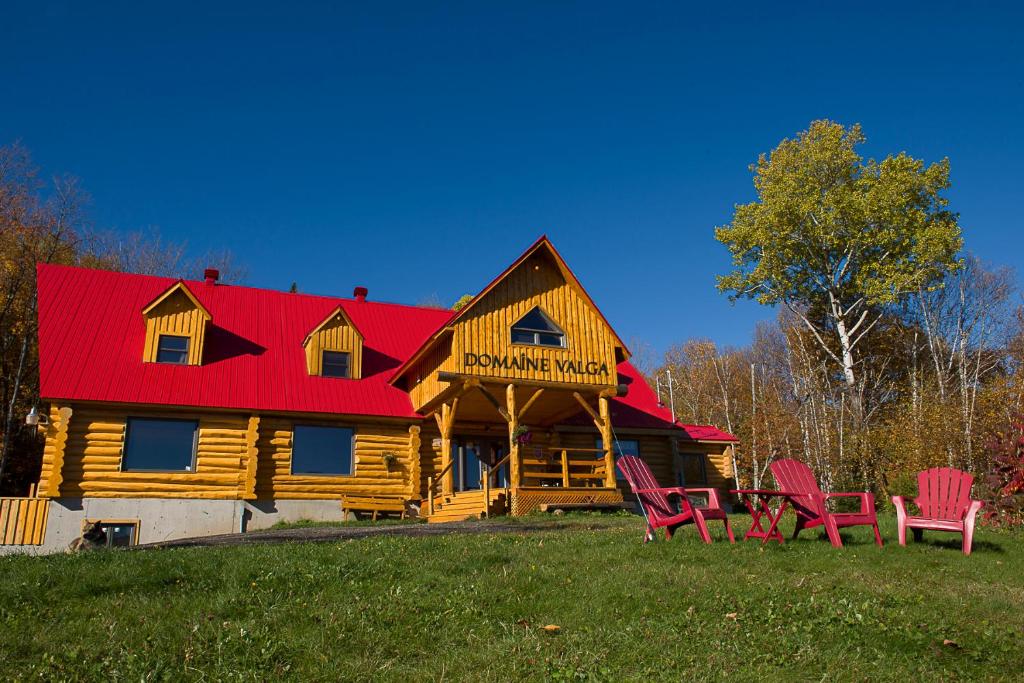 a log cabin with red chairs in front of it at Domaine Valga in Saint-Gabriel