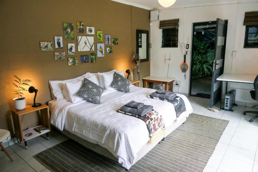 a bedroom with a large white bed with pictures on the wall at Canary Cottage in Greyton