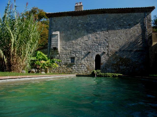 a large pool of water in front of a stone building at La Mouline de Belin in Lectoure