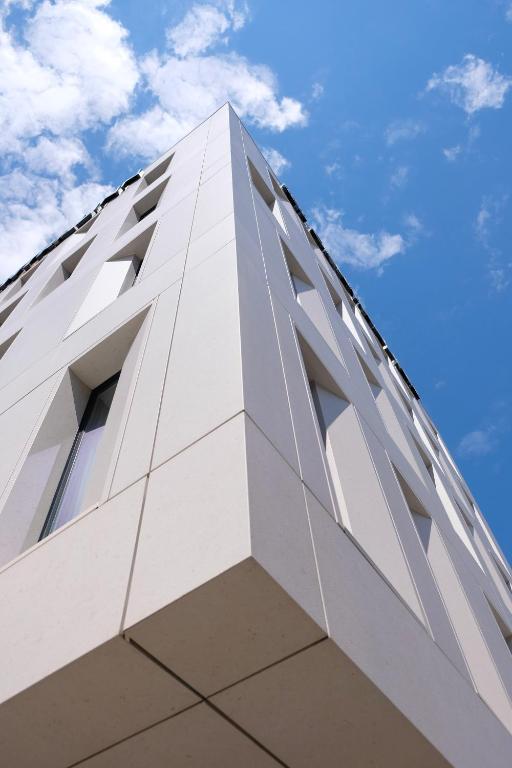 a tall white building against a blue sky at Centrale Hotel in Tirana